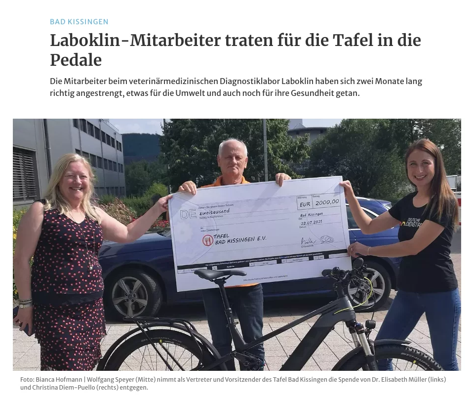 A newspaper article with the headline "Laboklin employees pedaled for the food bank." The picture shows three people holding a large symbolic check for €2,000. On the left is a woman, in the middle is a man, and on the right is a woman in a "Deutsche Dienstrad" shirt, standing in front of a bike.